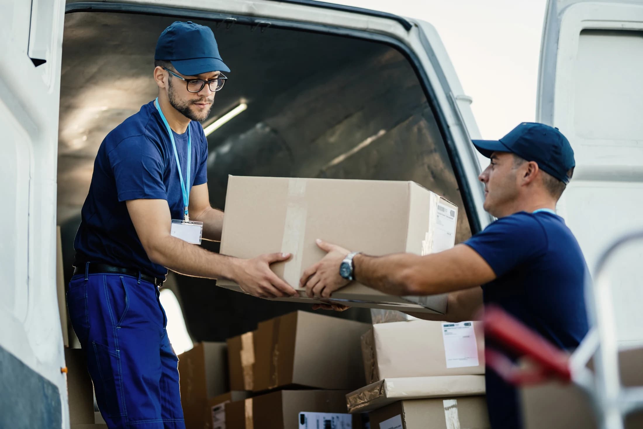 Two workers moving cartons from a delivery van